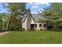 Cottage-style home with stone chimney surrounded by mature trees and landscaping at 2601 Semmes St, Atlanta, GA 30344