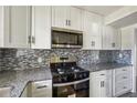Modern kitchen features white cabinets, stainless steel appliances, granite countertops, and decorative backsplash at 2391 Cove Rd, Lithonia, GA 30058
