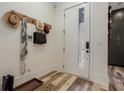 A modern entryway features light walls, a wooden coat rack with hats, a sleek door, and unique wood flooring at 1168 Mado Loop, Chattahoochee Hills, GA 30268