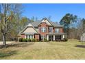 Charming brick home with a covered front porch, well-manicured lawn, and mature trees at 7090 Blue Sky Drive, Locust Grove, GA 30248