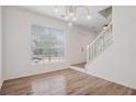 Bright entryway with hardwood floors, large window, modern lighting fixture, and white staircase at 6244 Marbut Farms Trl, Lithonia, GA 30058