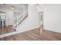 Bright entryway with hardwood floors, white staircase and banister, and modern lighting fixtures at 6244 Marbut Farms Trl, Lithonia, GA 30058