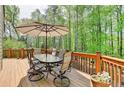 Relaxing outdoor deck area featuring a dining table set and wooded views at 955 Bishopswood Pl, Johns Creek, GA 30022