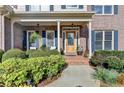 Inviting front porch with decorative plants, outdoor seating and a beautiful wooden front door at 5717 Harmony Point Dr, Lilburn, GA 30047