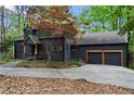 View of home showing the attached garage, landscaped front yard, and wooded surroundings at 1890 Spalding Dr, Atlanta, GA 30350