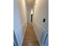 Hallway with white walls, decorative trim, and beautiful light wood-look floors at 5760 Old Carriage Dr, Atlanta, GA 30349
