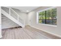 Bright living room featuring hardwood floors, modern staircase, and natural light from the large window at 2622 Terrace Pkwy, Morrow, GA 30260
