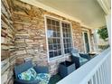 Cozy front porch with stone accents, seating, and well-manicured landscaping at 4658 Glory Maple Trce, Powder Springs, GA 30127