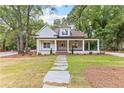 Inviting home featuring a spacious front porch, stone pathway, and beautifully landscaped yard at 159 Forest Ave, Social Circle, GA 30025