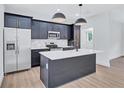 A modern kitchen showcases blue cabinets, stainless steel appliances, and a central island with stylish pendant lighting at 2000 Grove Ave, East Point, GA 30344