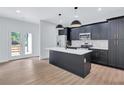 An open kitchen features stylish cabinets, a modern island, stainless steel appliances and access to the backyard at 2000 Grove Ave, East Point, GA 30344