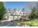 Side view of white brick home, showcasing three-car garage, and manicured lawn at 3224 Lanier Ne Dr, Atlanta, GA 30319