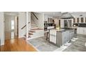 Open-concept kitchen with a large center island, staircase, stainless steel appliances, and white cabinetry at 3762 Frederica Rd, Berkeley Lake, GA 30096