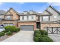 Two-story brick and stone townhome with gray garage doors and manicured landscaping at 5649 Cobblestone Creek Pl # 13, Mableton, GA 30126
