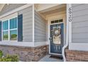 Close-up of the front door with a decorative wreath, side lights, and brick accents at 6920 Oak Valley Dr, Douglasville, GA 30134