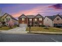 Beautiful brick home featuring a manicured lawn, blossoming tree, and a paved driveway at 2620 Paddock Point Pl, Dacula, GA 30019