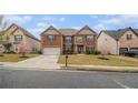 Well-maintained brick home with blossoming tree, a paved driveway, and a lush front lawn at 2620 Paddock Point Pl, Dacula, GA 30019
