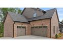 Attached two car garage doors with decorative details and coach lights in brick facade at 6120 Hutchins Dr, Buford, GA 30518