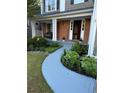 Inviting home exterior featuring a brick facade, covered porch, and a beautifully landscaped walkway leading to the front door at 9030 Brockham Way, Johns Creek, GA 30022
