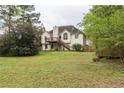 Large backyard featuring mature trees and a deck with stairs to the lower level at 703 Paul Revere Dr, Locust Grove, GA 30248