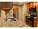 Kitchen featuring granite counters, black appliances, tile backsplash and wood cabinetry at 703 Paul Revere Dr, Locust Grove, GA 30248