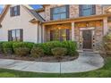 Inviting front entrance with brick accents, a decorative wreath, and lush landscaping at 5705 Windjammer Pt, Cumming, GA 30041