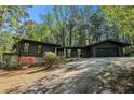 One story home with a black exterior, stone accents, a paved driveway, and mature trees at 2568 Sugarplum Ne Ct, Atlanta, GA 30345