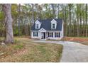 A charming two-story home surrounded by trees with a driveway leading up to the front of the house at 214 Walton St, Loganville, GA 30052