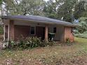 Rear exterior view of a brick house with a covered patio area and lush foliage at 2369 Christian Cir, Covington, GA 30016