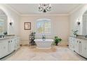 Luxurious bathroom with a freestanding tub, double vanities, and travertine flooring at 931 Fairfield Dr, Marietta, GA 30068