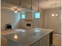 Open-concept space with a kitchen island featuring a quartz countertop overlooking a fireplace and living area at 30 Riverrock Trl, Dallas, GA 30157