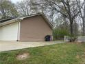 Side view of home showing tan siding and back of garage with trash can at 1430 Country Lane Ne Dr, Conyers, GA 30012