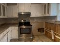 View of kitchen featuring stainless steel stove, white cabinets and tile backsplash at 1430 Country Lane Ne Dr, Conyers, GA 30012