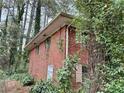 Side exterior of brick home surrounded by lush greenery and mature trees at 6079 Zachary Ct, Norcross, GA 30093