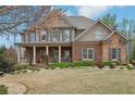 Inviting two-story home with a brick facade, covered porch, and meticulously maintained landscaping at 1870 Marcia Overlook Dr, Cumming, GA 30041