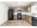 Kitchen featuring painted cabinets, black appliances, and worn vinyl flooring at 116 Shefield Pl, Douglasville, GA 30134