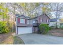 Split-level home featuring neutral siding, red shutters, and attached garage at 3094 Calumet Nw Cir, Kennesaw, GA 30152