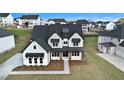 Aerial view featuring a white brick home with black accents and a manicured lawn in a suburban neighborhood at 7785 Wild Violet Dr, Cumming, GA 30040