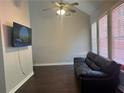 Living room with vaulted ceilings, hardwood floors, television, and a modern black leather couch at 5915 Windsorcreek Dr, Douglasville, GA 30135