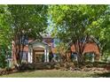 Traditional brick home featuring a well-manicured front yard, mature trees, and classic architectural details at 3895 Overlake Dr, Cumming, GA 30041