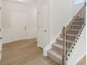 Bright entryway with wood-look flooring and a staircase featuring a wood handrail and black iron balusters at 28 Kensington St, Kingston, GA 30145