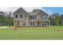 Charming home with gray and brick exterior, set on a spacious lawn with beautiful, mature trees at 205 Haverling Pass, Hampton, GA 30228