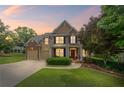 Charming two-story home features a well-manicured lawn and inviting curb appeal at twilight at 6597 River Island Dr, Buford, GA 30518