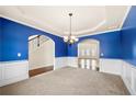 Bright dining room featuring blue accent walls, modern chandelier, and archways to living spaces at 3750 Lake Haven Way, Atlanta, GA 30349