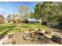 Inviting backyard with a stone fire pit surrounded by wooden stump seating and a spacious grassy area at 1488 Drayton Woods Dr, Tucker, GA 30084