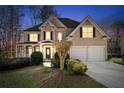 Charming two-story home at dusk features a landscaped yard and an attached two-car garage at 2405 Millwater Xing, Dacula, GA 30019