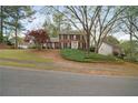 Classic brick home on a well-manicured lawn with lush greenery and mature trees providing shade and privacy at 4292 Rocky Ne Gln, Roswell, GA 30075
