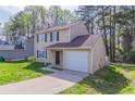 Charming tan two-story home featuring an attached one car garage and a driveway at 2030 Hilda Burns Pl, Lithonia, GA 30058