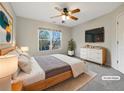 This light-filled bedroom features neutral paint, ceiling fan, a large window, and a sleek dresser with television at 2123 Tigger Ne Trce, Marietta, GA 30066