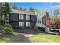 Charming exterior of a two-story home featuring dark siding, a stone chimney, and beautiful landscaping at 11630 Mountain Laurel Dr, Roswell, GA 30075